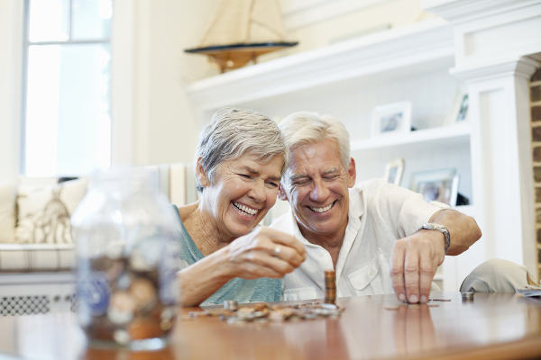 Cheerful senior couple counting coins at table